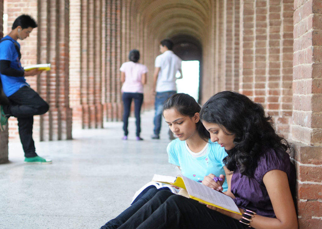 Students studying in outdoor hallway of a college campus.