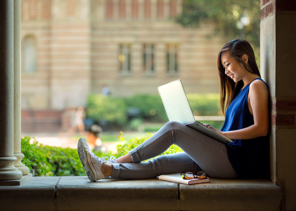 students study outdoors at a college campus.