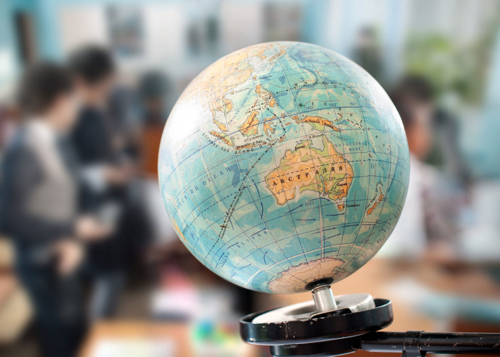A globe is in the foreground, while business professionals are faded in the background.