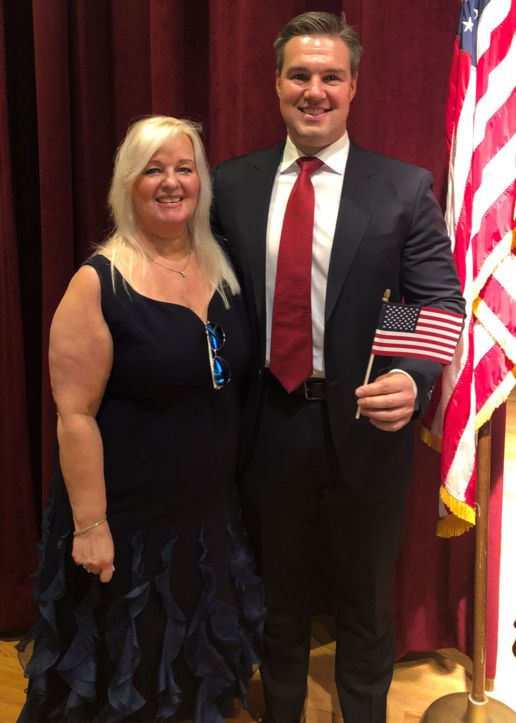 Matt Nicholson stands with his mom after the naturalization Ceremony holding an american flag