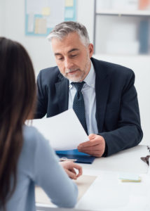 An HR professional sits with a new hire and goes over paperwork